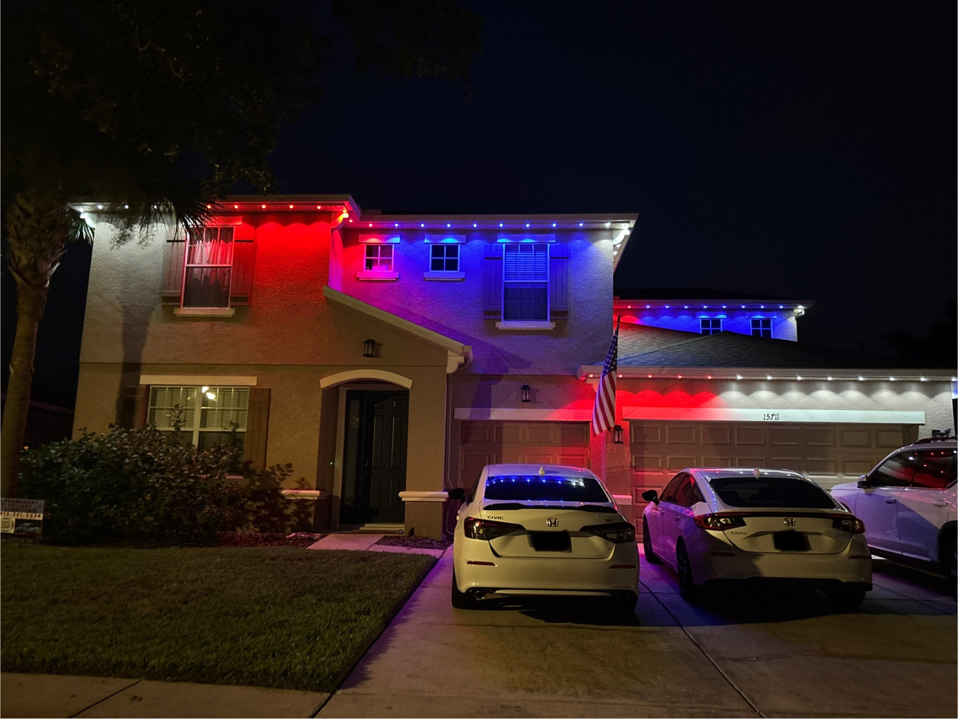 Red, white, and blue permanent roofline lighting on a two-story home